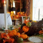 thanksgiving-tablescapes: a rustic cornucopia filled with mini pumpkins, white candles and green glasses