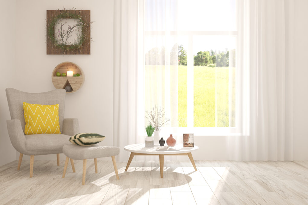 A farmhouse living room with a chair, table, and white curtains.